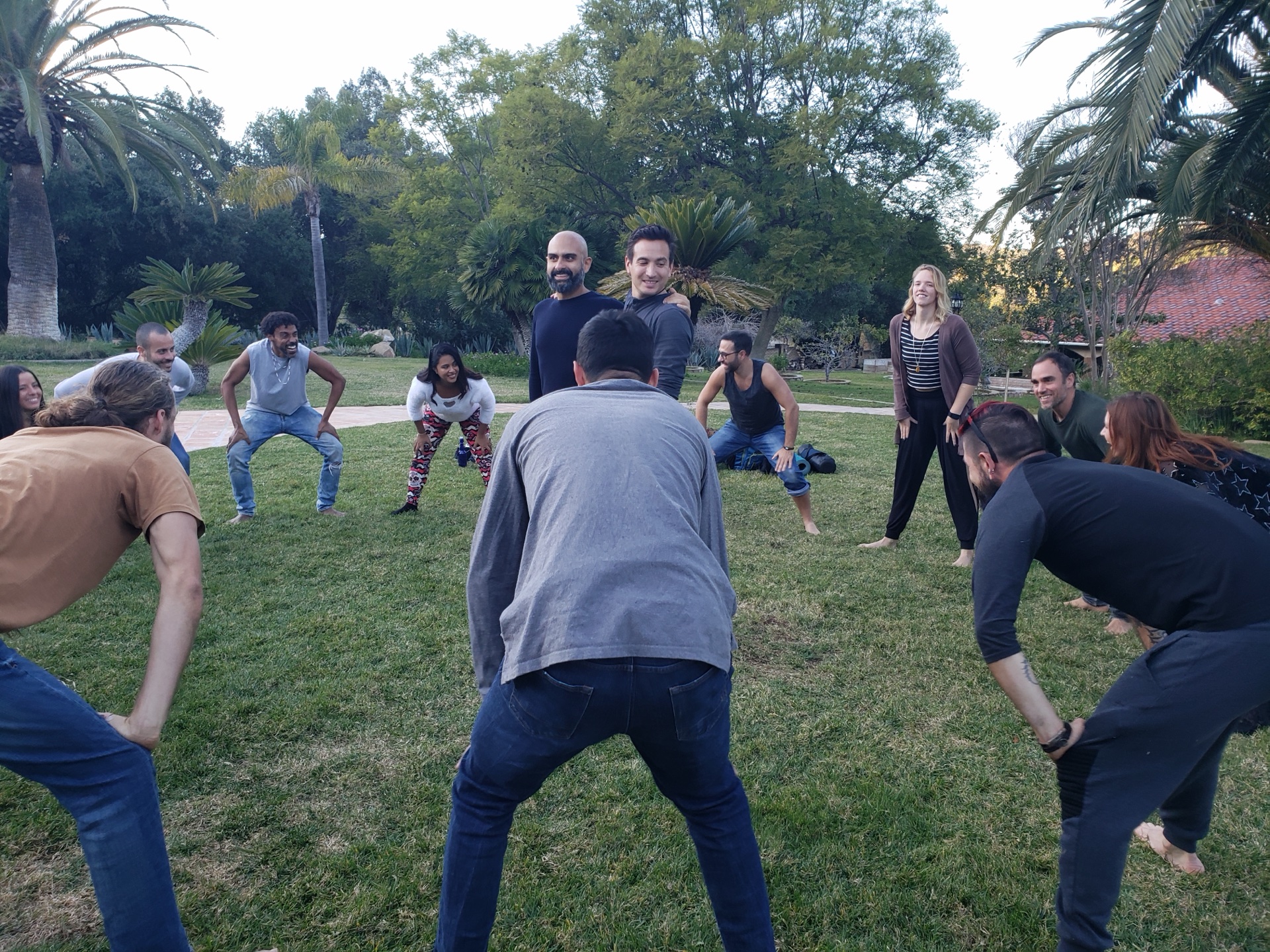 Workshop participants squatting in a circle outdoors in a park